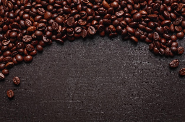 Grãos de café torrados na superfície texturizada escura. Copiar espaço