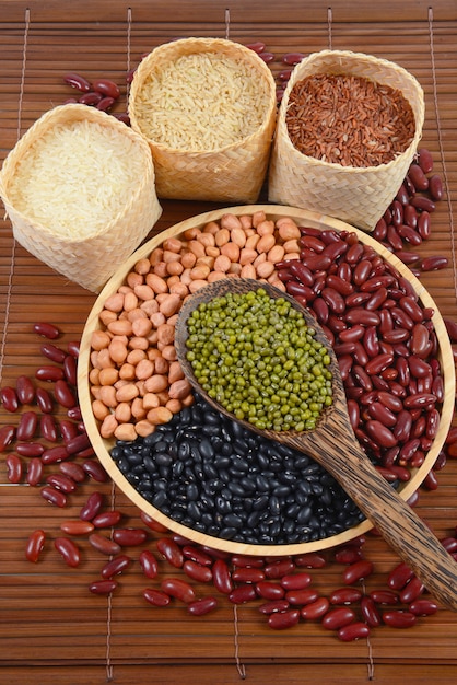 Grãos de cereais e sementes de feijão e arroz branco útil para a saúde em colheres de madeira.