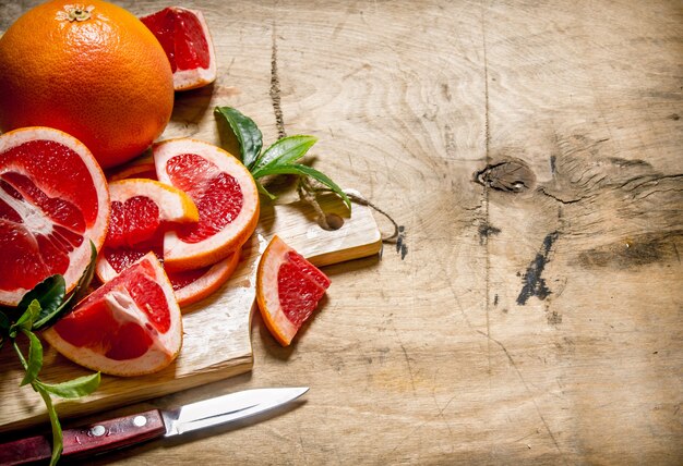 Grapefruit fatiado na placa de madeira com folhas na mesa de madeira.