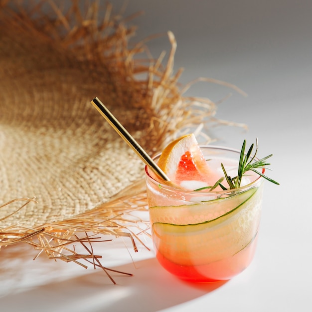 Grapefruit-Gurken-Gin-Cocktail auf eleganten Gläsern mit Strohhut auf weißem Hintergrund