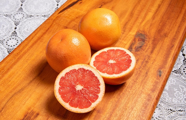 Grapefruit mehrere Grapefruits und eine halbiert auf einem selektiven Fokus der rustikalen Holzoberfläche