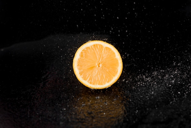 Grapefruit mit Wassertropfen auf schwarzer Oberfläche