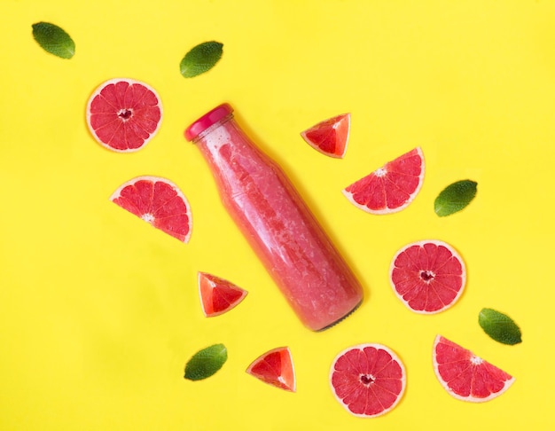 Grapefruit-Smoothie in einer Glasflasche auf gelben Hintergrund Top-View Closeup