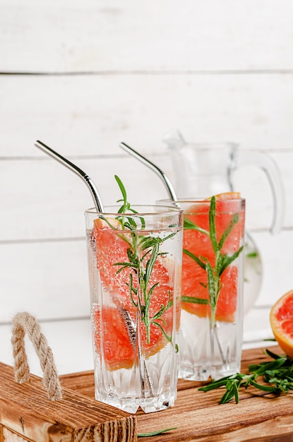 Grapefruit-Tonic-Wasser mit Rosmarin auf weißem Holzraum. Gesunder Lebensstil. Trinkhalme aus Metall