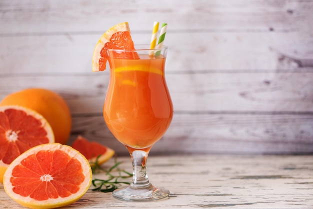 Grapefruitsaft im Glas und frische Grapefruitscheiben auf hellem Holztisch mit Kopierraum