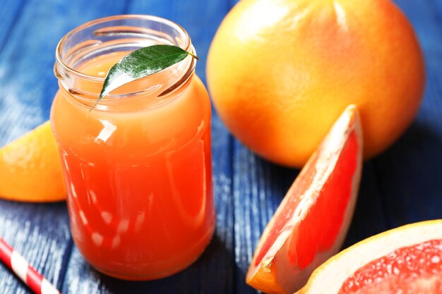 Grapefruitsaft in Flaschen und frische Früchte auf dunkelblauem Holzhintergrund