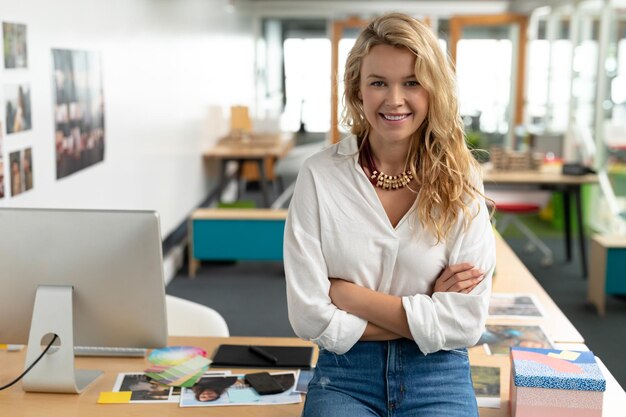 Foto graphikerin mit gekreuzten armen sitzt an einem schreibtisch in einem modernen büro