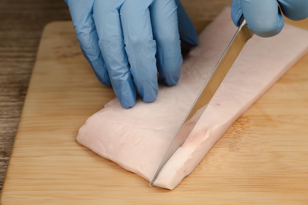 La grasa se corta en pedazos pequeños Las manos de un cocinero cortan la mantequilla con un cuchillo en pedacitos pequeños para preparar comida cocina casera