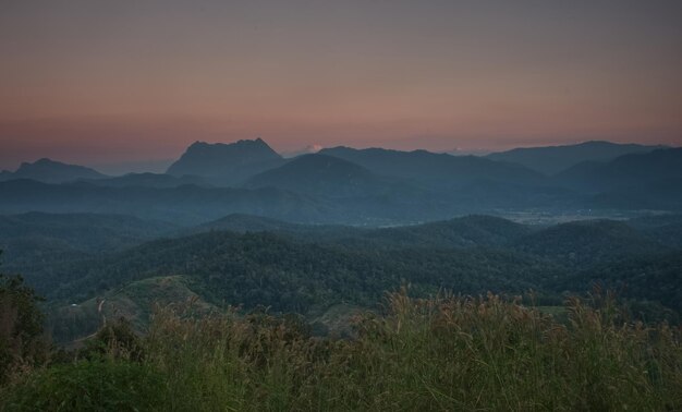 Grasfeld mit buntem Bergkettenhintergrund in der Sonnenuntergangzeit