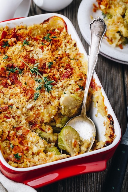 Gratinado de coles de bruselas al horno con tocino y pan rallado sobre fondo de madera