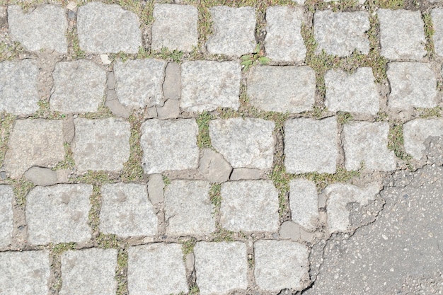 Graue alte Pflaster-Draufsicht oder Granit-Kopfsteinpflaster-Straße. Antiker gepflasterter Ziegelboden oder Straße mit Granitfliesen mit großen Steinen