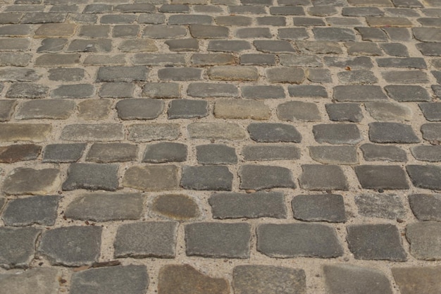 Graue alte Pflaster-Draufsicht oder Granit-Kopfsteinpflaster-Straße. Antiker gepflasterter Ziegelboden oder Straße mit Granitfliesen mit großen Steinen