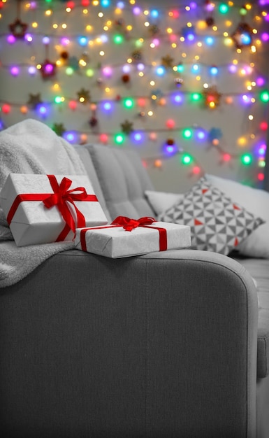 Graue Couch mit Geschenken auf Weihnachtslichthintergrund