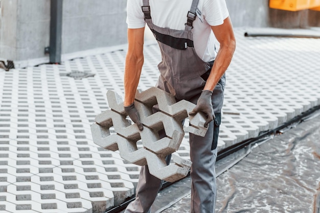 Foto graue kleidung junger mann, der tagsüber in uniform auf dem bau arbeitet