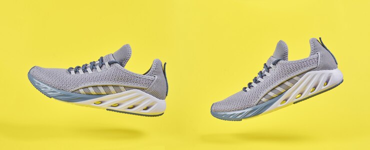 Graue Sportschuhe zum Laufen auf gelber Wand. Konzept für gesunden Lebensstil, Sport und Fitness. Farbe 2021 Jahr. Modekissen Turnschuhe.