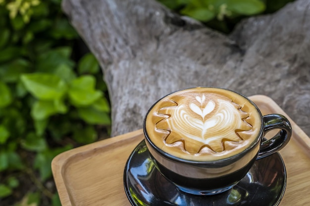 Graue Tasse frischer Cappuccino mit Latte Art auf dem Holztischhintergrund