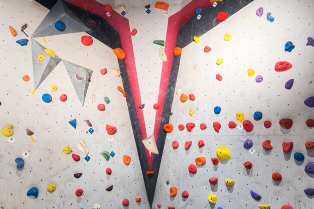 Graue Wand mit Klettergriffen und Seilen in der Turnhalle. Kletterkonzept.