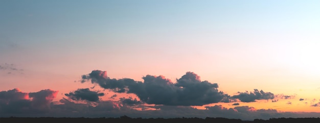 Graue Wolken, die von der Sonne auf einem Himmelshintergrund mit Farbverlauf beleuchtet werden