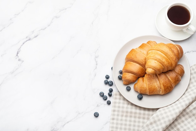 grauer Hintergrund mit Frühstück Croissants mit Kaffee und Beeren