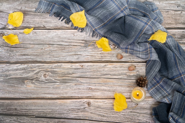 Grauer Schal und trockene Blätter von gelber Farbe auf Holzoberfläche