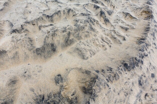 Grauer Stein (oder Teil des Felsens) bedeckte Sand als abstrakten Hintergrund mit interessantem Maßwerk.