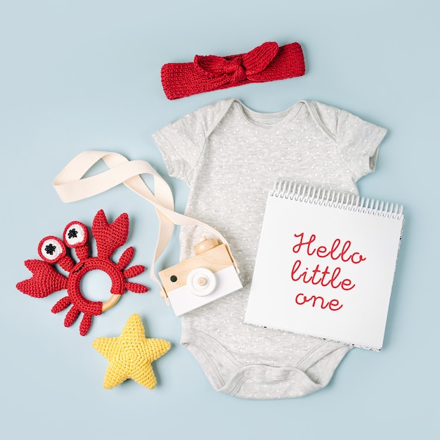 Foto grauer süßer babybody mit mock-up-karte. set kinderkleidung und accessoires. mode neugeborenes. flache lage, ansicht von oben