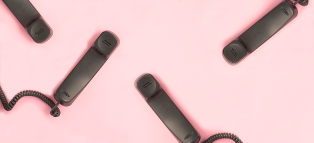 Grauer Telefonhörer auf rosafarbenem Hintergrund Muster flach Draufsicht