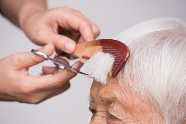 graues Haar der älteren Frau schneiden