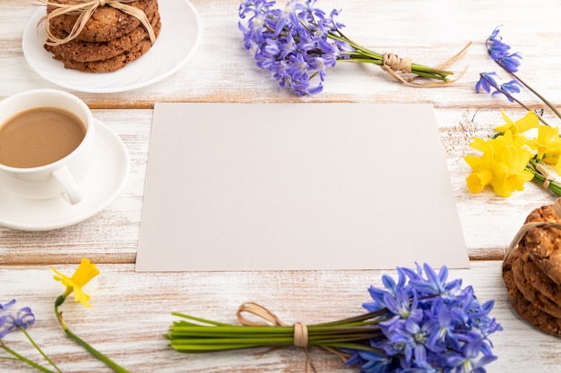 graues Papier mit Haferkeksen, Frühlingsschneeglöckchen, Glockenblumen, Narzissen und Tasse Kaffee