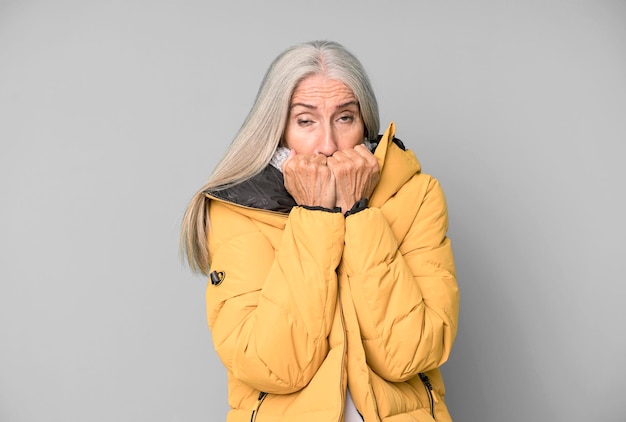 Grauhaarige ältere hübsche Frau, die einen Anorak-Winter und ein kaltes Konzept trägt