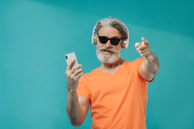 Grauhaariger älterer Mann mit Sonnenbrille posiert mit einem Telefon Studio-Shooting