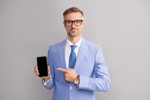 Grauhaariger Mann, der in Anzug und Brille mit dem Finger auf das Telefon zeigt, Präsentation