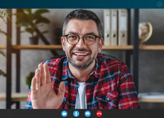 Foto grauhaariger mann, der video-chat in der büroansicht von der webkamera verwendet