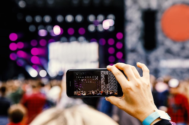 Foto gravando um concerto em um telefone celular, palco ao ar livre.