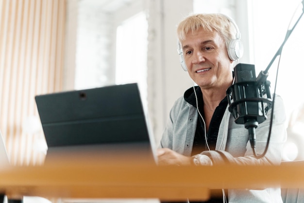 Gravando um streamer de podcast de áudio adulto masculino usando um laptop e microfone online