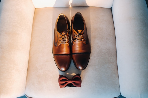 Foto gravata-borboleta marrom sobre um fundo claro e botas.