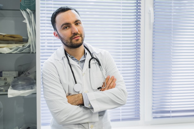 Grave doctor masculino con los brazos cruzados en su oficina