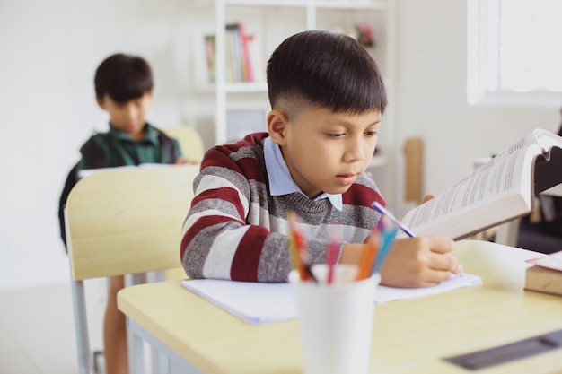 Grave estudiante asiático haciendo tareas en el aula