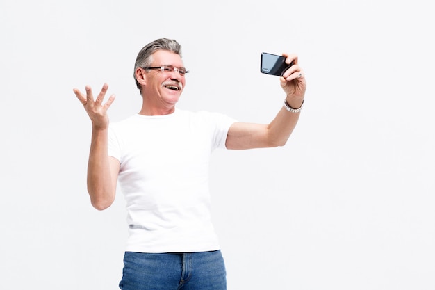 Grave homem sênior fazendo selfie no smartphone, vovô, levando um estilo de vida ativo.