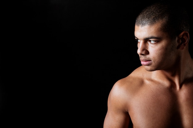 Foto grave joven afroamericano desnudo de pie y mirando a otro lado