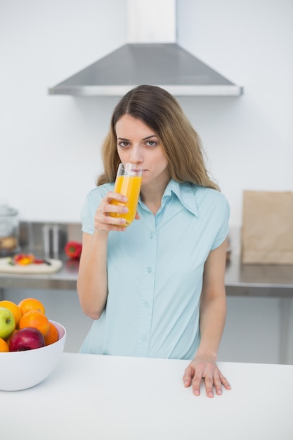 Grave joven bebiendo un vaso de jugo de naranja