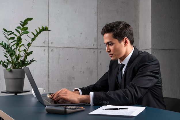 Grave joven escribiendo en la computadora portátil en la oficina