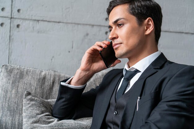 Grave joven hablando por teléfono en un sillón