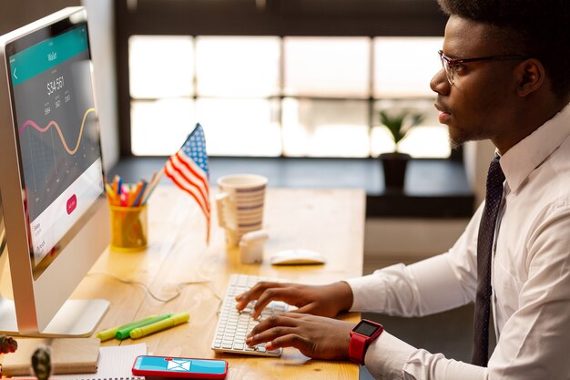 Grave joven mirando la pantalla de la computadora mientras revisa las estadísticas financieras