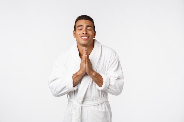 Grave joven pacífico con las manos unidas meditando.