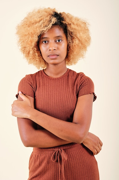 Grave mujer afro mirando a la cámara mientras posa sobre un fondo aislado.