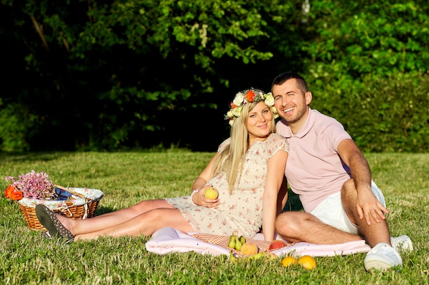 Grávida casal no parque natural em um piquenique no verão