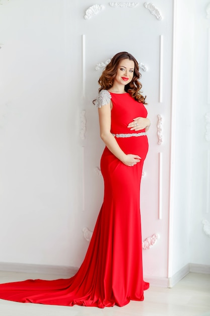 Grávida mulher linda em um elegante vestido vermelho