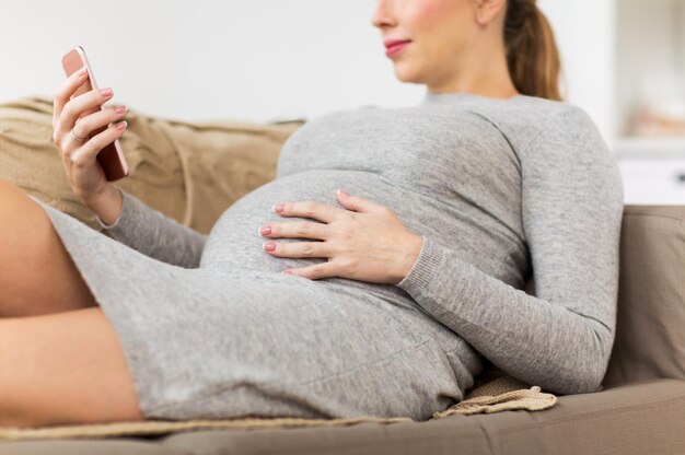 gravidez, tecnologia e conceito de pessoas - close de mulher grávida feliz com smartphone em casa
