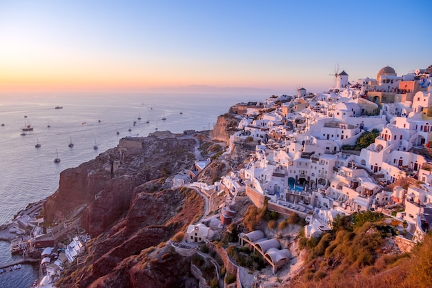 Grecia. Casas y tejados blancos en la isla de Santorini (Thira). Muchos barcos con turistas van al mar para conocer la puesta de sol.